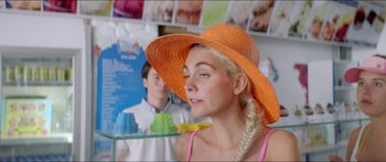 Movie still from “Holiday” (2018), directed by Isabella Eklöf – A woman wearing an orange straw hat and a pink tank top; Close Up shot, Over the shoulder angle