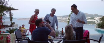Movie still from “Holiday” (2018), directed by Isabella Eklöf – A group of people standing around a table; Medium shot, High angle