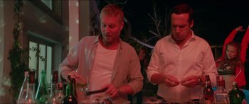 Movie still from “Holiday” (2018), directed by Isabella Eklöf – Two men standing in front of each other at a party; Medium shot, Low angle