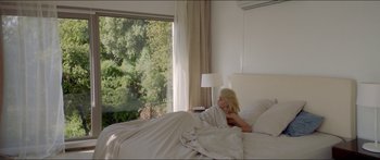 Movie still from “Holiday” (2018), directed by Isabella Eklöf – A woman laying in a bed next to a window; Wide shot, High angle