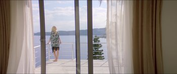 Movie still from “Holiday” (2018), directed by Isabella Eklöf – A woman standing on a deck looking out at the water; Wide shot, High angle