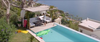 Movie still from “Holiday” (2018), directed by Isabella Eklöf – Two people sitting on a couch next to a swimming pool; Extreme Wide shot, High angle