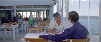 Movie still from “Holiday” (2018), directed by Isabella Eklöf – Two men sitting at a table in front of each other; Medium shot, Over the shoulder angle