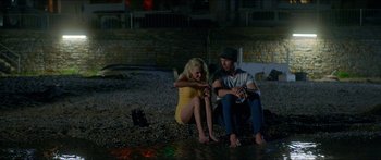 Movie still from “Holiday” (2018), directed by Isabella Eklöf – A man and a woman sitting next to each other on the beach; Wide shot, High angle
