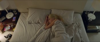 Movie still from “Holiday” (2018), directed by Isabella Eklöf – A woman is sleeping in a bed with white sheets; Medium shot, Overhead angle