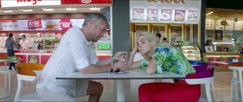 Movie still from “Holiday” (2018), directed by Isabella Eklöf – A man and a woman sitting at a table; Medium shot, High angle