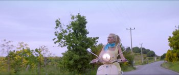 Movie still from “Holiday” (2018), directed by Isabella Eklöf – A woman riding on the back of a moped; Wide shot, Low angle