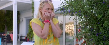 Movie still from “Holiday” (2018), directed by Isabella Eklöf – A woman in a yellow shirt is holding her hands to her face; Medium shot, Over the shoulder angle