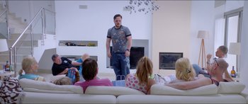 Movie still from “Holiday” (2018), directed by Isabella Eklöf – A group of people sitting in a living room; Wide shot, Over the shoulder angle