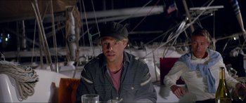 Movie still from “Holiday” (2018), directed by Isabella Eklöf – A man sitting at a table with a glass of water; Medium shot, Over the shoulder angle