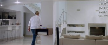 Movie still from “Holiday” (2018), directed by Isabella Eklöf – A woman standing next to a couch holding a glass of wine; Wide shot, Low angle