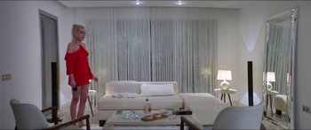 Movie still from “Holiday” (2018), directed by Isabella Eklöf – A living room filled with furniture and a large window covered in curtains; Wide shot, High angle
