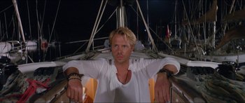 Movie still from “Holiday” (2018), directed by Isabella Eklöf – A man in a white shirt is sitting on a boat at night; Close Up shot, Low angle