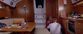 Movie still from “Holiday” (2018), directed by Isabella Eklöf – Two women sitting on a boat in a room; Wide shot, High angle