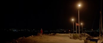 Movie still from “Holiday” (2018), directed by Isabella Eklöf – A person standing on top of a sandy beach at night; Extreme Wide shot, High angle