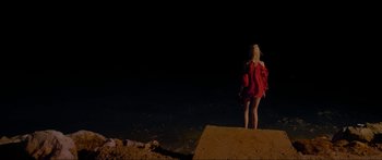 Movie still from “Holiday” (2018), directed by Isabella Eklöf – A woman in a red dress standing on top of a hill at night; Wide shot, High angle