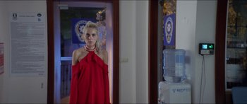 Movie still from “Holiday” (2018), directed by Isabella Eklöf – A girl in a red dress is standing in front of a mirror; Medium shot, Over the shoulder angle