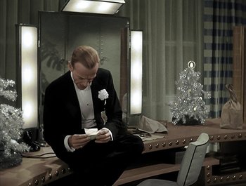 Movie still from “Holiday Inn” (1942), directed by Robert Allen – A man in a tuxedo sitting in front of a laptop; Medium shot, High angle