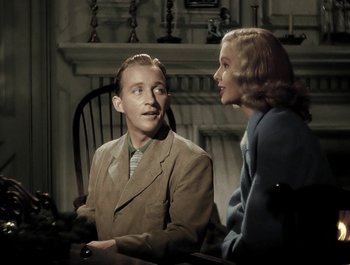 Movie still from “Holiday Inn” (1942), directed by Robert Allen – A man and a woman sitting in front of a fireplace; Medium shot, Low angle