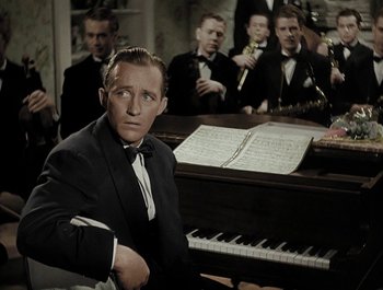 Movie still from “Holiday Inn” (1942), directed by Robert Allen – A man in a suit sitting in front of a grand piano; Medium shot, High angle