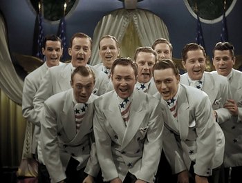 Movie still from “Holiday Inn” (1942), directed by Robert Allen – A group of men in white suits posing for a picture; Medium shot, High angle