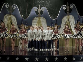 Movie still from “Holiday Inn” (1942), directed by Robert Allen – A group of men and women standing in front of a stage; Wide shot, High angle