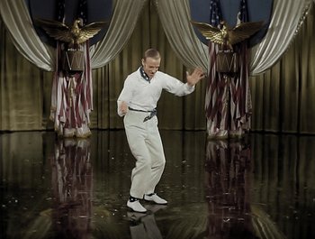 Movie still from “Holiday Inn” (1942), directed by Robert Allen – A man in white shirt and white pants standing on a stage; Wide shot, High angle