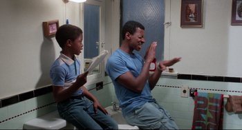 Movie still from “Hollywood Shuffle” (1987), directed by Robert Townsend – A man and a boy are playing wii in a bathroom; Medium shot, Over the shoulder angle