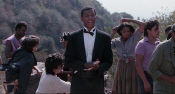 Movie still from “Hollywood Shuffle” (1987), directed by Robert Townsend – A man wearing a suit and bow tie; Medium shot, Low angle