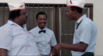 Movie still from “Hollywood Shuffle” (1987), directed by Robert Townsend – A group of men standing next to each other; Medium shot, Low angle