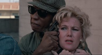 Movie still from “Hollywood Shuffle” (1987), directed by Robert Townsend – A man holding a gun next to a woman; Close Up shot, High angle