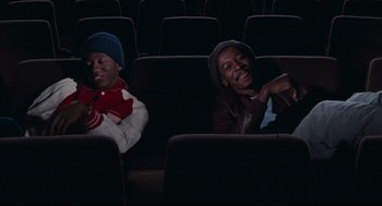 Movie still from “Hollywood Shuffle” (1987), directed by Robert Townsend – Two men sitting in a theater with their eyes closed; Medium shot, High angle