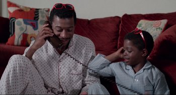Movie still from “Hollywood Shuffle” (1987), directed by Robert Townsend – A man sitting on a couch talking on the phone; Medium shot, High angle