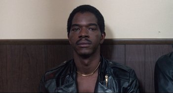 Movie still from “Hollywood Shuffle” (1987), directed by Robert Townsend – A man wearing a leather jacket and a gold necklace; Close Up shot, Low angle