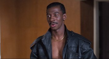 Movie still from “Hollywood Shuffle” (1987), directed by Robert Townsend – A man in a black leather jacket with a gold chain around his neck; Close Up shot, High angle