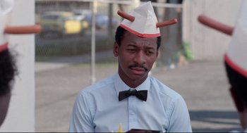 Movie still from “Hollywood Shuffle” (1987), directed by Robert Townsend – A man wearing a paper hat with antlers on it; Close Up shot, Over the shoulder angle