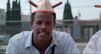 Movie still from “Hollywood Shuffle” (1987), directed by Robert Townsend – A man wearing a paper hat and smiling for the camera; Close Up shot, Low angle