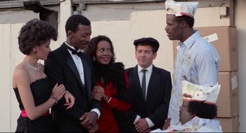 Movie still from “Hollywood Shuffle” (1987), directed by Robert Townsend – A group of people standing next to each other; Medium shot, Low angle