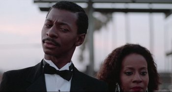 Movie still from “Hollywood Shuffle” (1987), directed by Robert Townsend – A man in a tuxedo standing next to a woman in a black dress; Close Up shot, Low angle