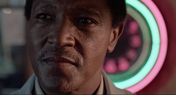 Movie still from “Hollywood Shuffle” (1987), directed by Robert Townsend – A man's face in front of a colorful background; Close Up shot, Low angle