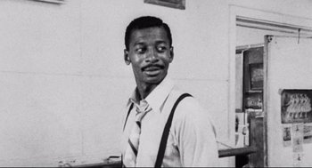 Movie still from “Hollywood Shuffle” (1987), directed by Robert Townsend – A black and white photo of a man wearing a tie; Close Up shot, Low angle