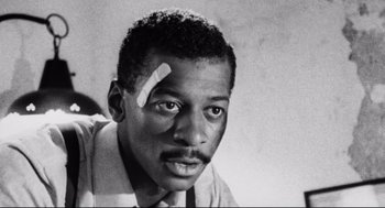 Movie still from “Hollywood Shuffle” (1987), directed by Robert Townsend – A black and white photo of a man with bandage on his head; Close Up shot, Low angle