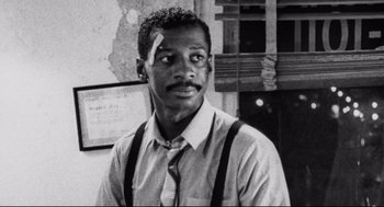 Movie still from “Hollywood Shuffle” (1987), directed by Robert Townsend – A black and white photo of a man with a bandage on his head; Close Up shot, Low angle