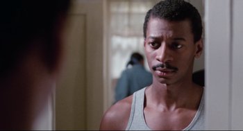 Movie still from “Hollywood Shuffle” (1987), directed by Robert Townsend – A person wearing a tank top; Close Up shot, Over the shoulder angle