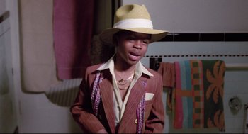Movie still from “Hollywood Shuffle” (1987), directed by Robert Townsend – A young man wearing a brown suit and a straw hat; Medium shot, High angle