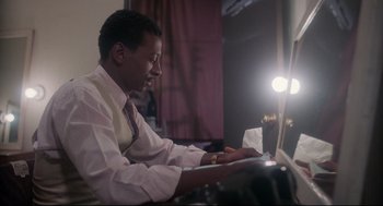 Movie still from “Hollywood Shuffle” (1987), directed by Robert Townsend – A man sitting at a table using a computer; Medium shot, High angle