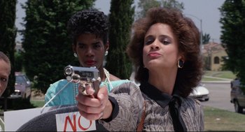 Movie still from “Hollywood Shuffle” (1987), directed by Robert Townsend – A woman holding a gun in front of another woman; Close Up shot, Low angle