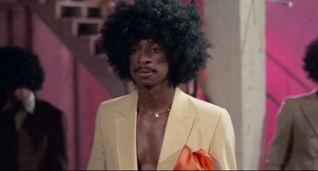 Movie still from “Hollywood Shuffle” (1987), directed by Robert Townsend – A man in a yellow suit with a black afro; Medium shot, Over the shoulder angle