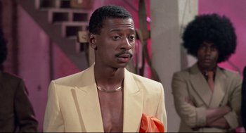 Movie still from “Hollywood Shuffle” (1987), directed by Robert Townsend – A man in a yellow suit and orange bow tie; Close Up shot, Over the shoulder angle
