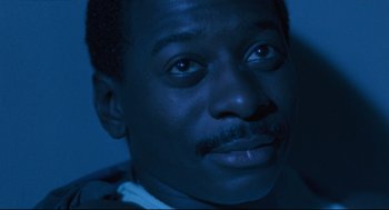 Movie still from “Hollywood Shuffle” (1987), directed by Robert Townsend – A man's face in the dark; Close Up shot, High angle